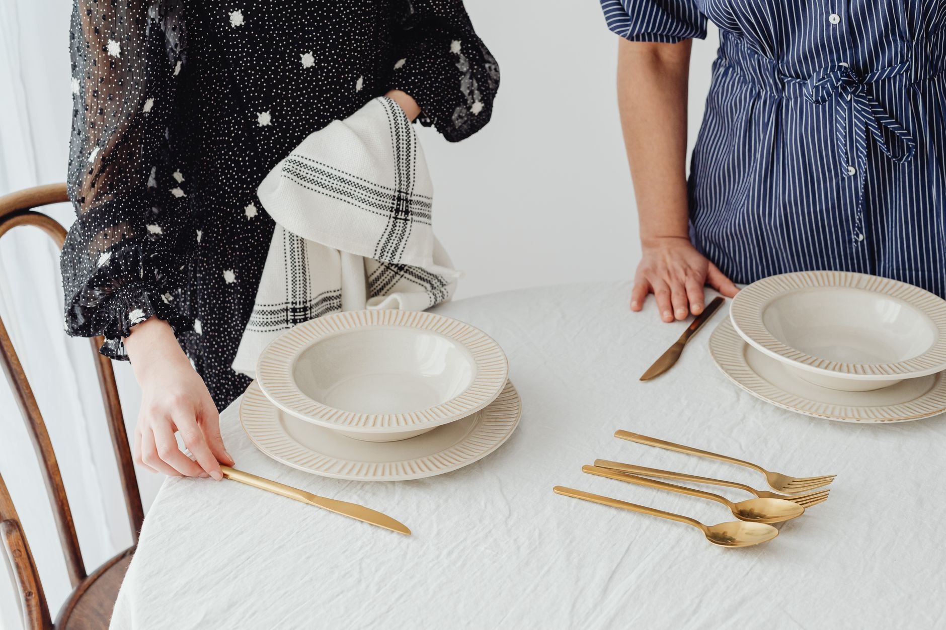 An elegantly styled table with gold cutlery and warm ceramic bowls on natural linen.